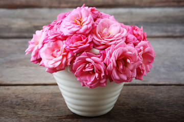 Beautiful pink roses in pot on wooden background