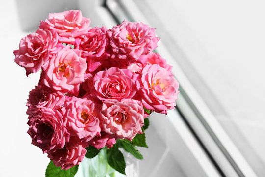 Bouquet of beautiful fresh roses on windowsill background