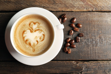 Cup of coffee latte art with grains on wooden background