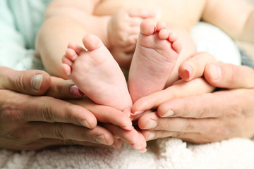 Obraz na płótnie Canvas Newborn baby feet on father and mother hands, close-up