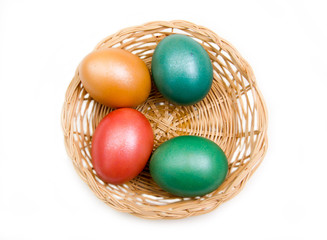 Basket with colored eggs on white background top view