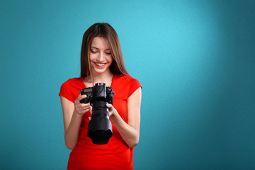 Young female photographer taking photos on blue background