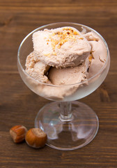 Cup of ice cream with hazelnut on wooden table top view