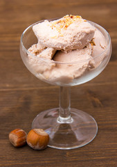 Cup of ice cream with hazelnut on wooden table
