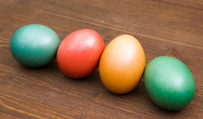 Oblique row of colored eggs on wooden table