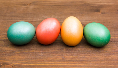 Fototapeta na wymiar Row of colored eggs on wooden table