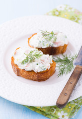 Canapes with soft cheese spread on white plate