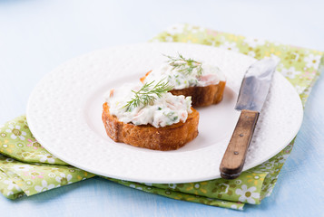 Canapes with soft cheese spread on white plate