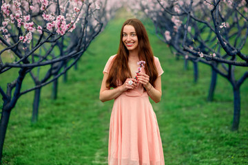 Woman enjoying spring in the green field with blooming trees
