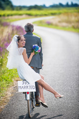 A newlywed couple is taking the road on a bike.