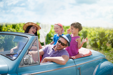 A lovely family is going on vacation in a convertible retro car