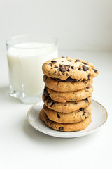 A stack of Biscuit cookies with chocolate chips and a glass of m