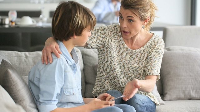 Mother giving warning to young boy using smartphone