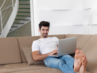 Man Relaxing On Sofa With Laptop