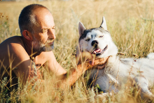 Old man plays with his dog Siberian Husky. Lifestyle. Active rec