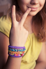 Caucasian girl showing two fingers with rubber loom bracelets