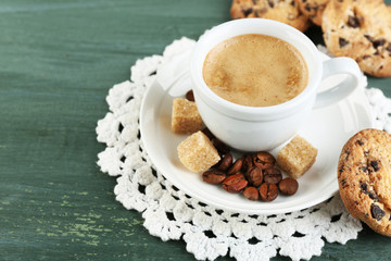 Cup of coffee and tasty cookie on color wooden background