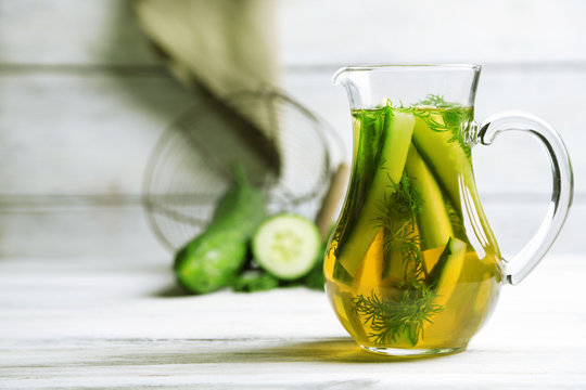 Glass ewer with fresh organic cucumber water on wooden table