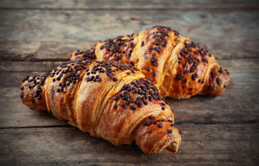 Fresh and tasty croissants with chocolate on wooden background