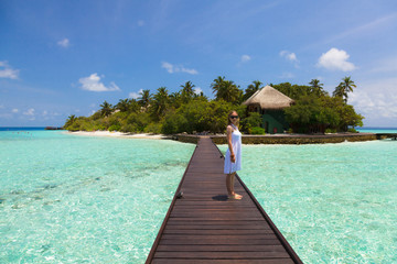 Girl in white dress standing on footbridge in the Maldives