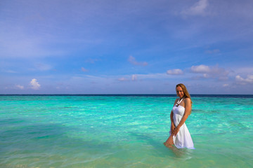 Fototapeta na wymiar Beautiful girl in white standing in water at Maldives
