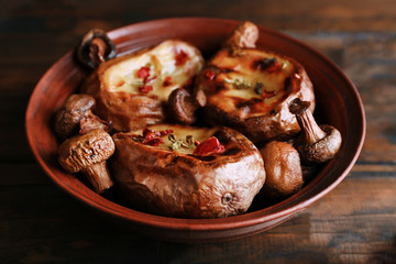 Baked potatoes with mushrooms in bowl on wooden background