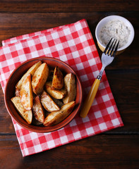 Baked potatoes in bowl and sauce on table close up