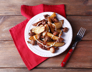 Baked potatoes with mushrooms and sauce on plate on wooden