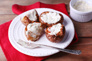 Baked potatoes with mushrooms and sauce on plate on wooden
