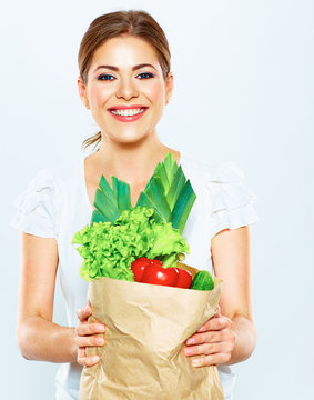 portrait of happy woman with green vegan food in paper bag.