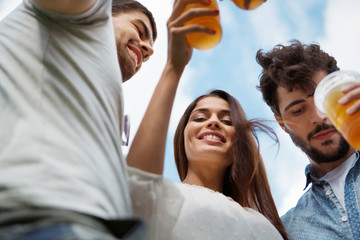 Vier Freunde mit Plastikbechern stoßen gemeisam an
