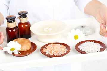 Beauty therapist holding tray of spa treatments, close-up