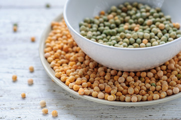 Two bowls with yellow and green peas on wooden white background