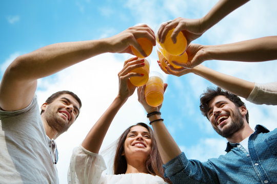 Vier Freunde mit Plastikbechern sto&szlig;en gemeisam an