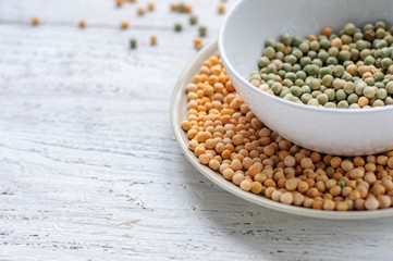 Two bowls with yellow and green peas on wooden white background