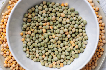 Two bowls with yellow and green peas on wooden white background