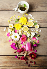 Cup of herbal tea with beautiful flowers, on wooden background