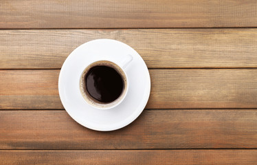 Cup of coffee on wooden table, top view