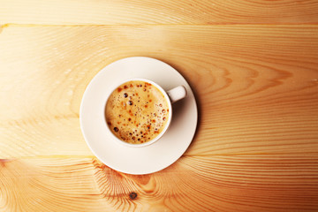 Cup of coffee on wooden table, top view