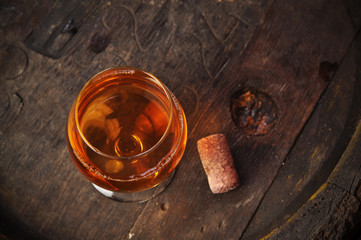 Glass of cognac on the vintage wooden barrel
