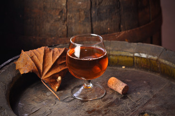 Glass of cognac on the vintage wooden barrel