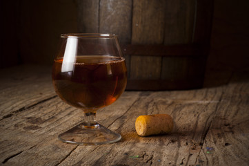 Glass of cognac on the vintage wooden barrel