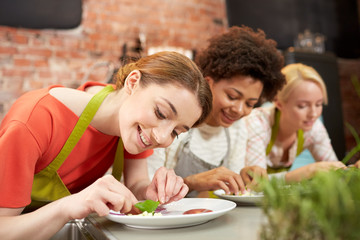 happy women cooking and decorating dishes