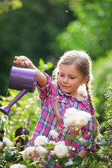 Mädchen im Garten gießt Blumen