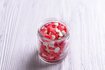 Colorful sprinkles in jar on table close-up