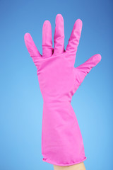 Rubber glove on hand, on blue background