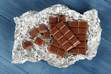 Chocolate in foil on wooden table, closeup