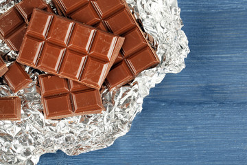 Chocolate in foil on wooden table, top view