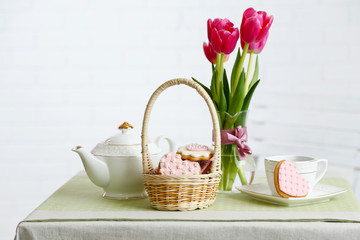 Tea set with flowers on table, on light background