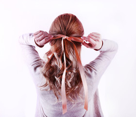 Female hairstyle with color ribbon on white wall background